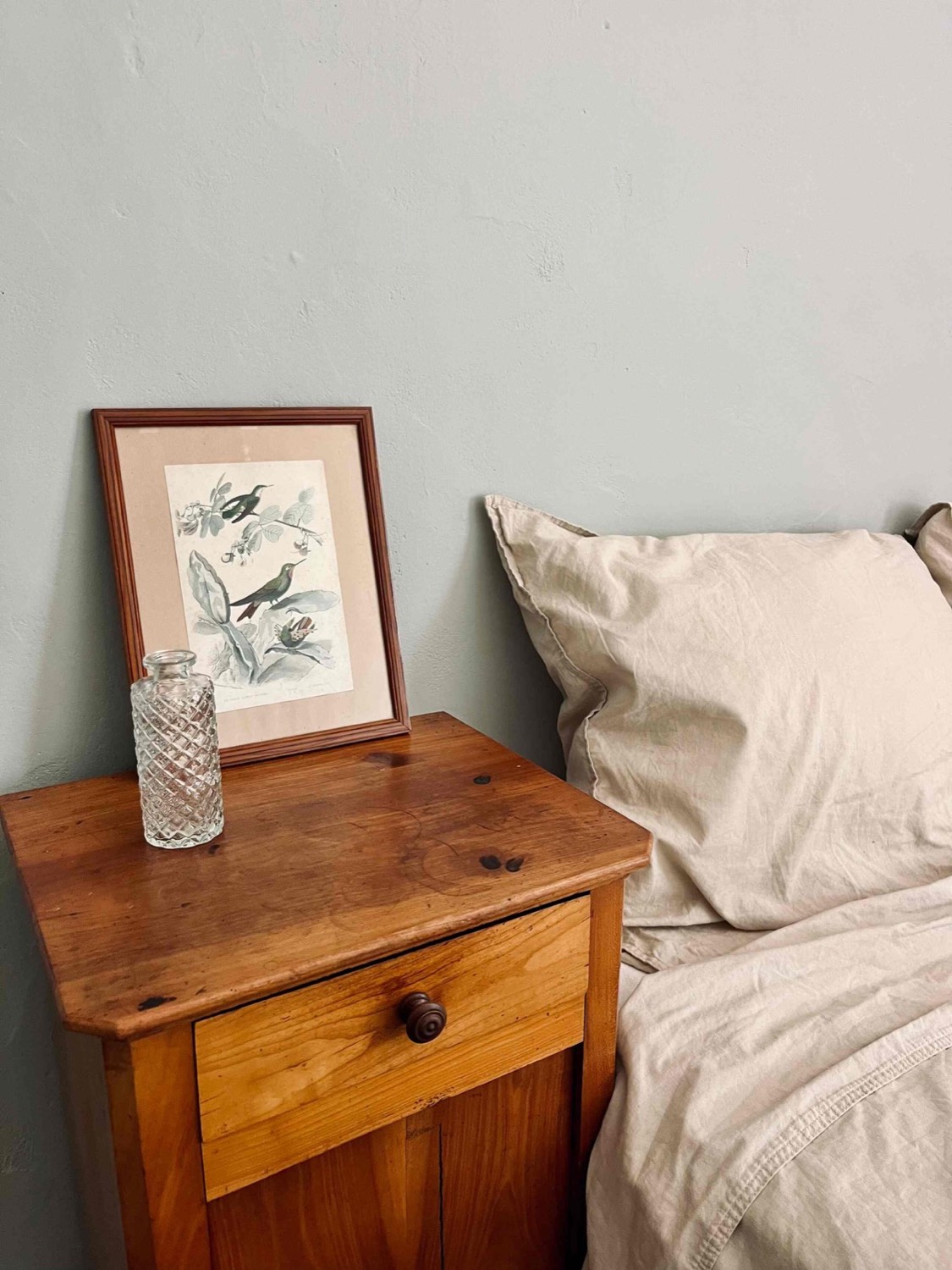 Chambre paisible : chevet en bois et gravure d'oiseau