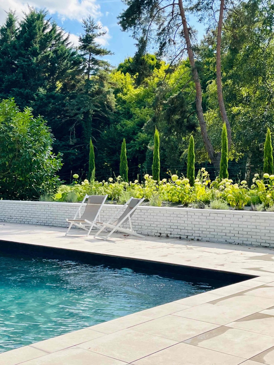 La piscine chauffée, transats et jardin fleuri